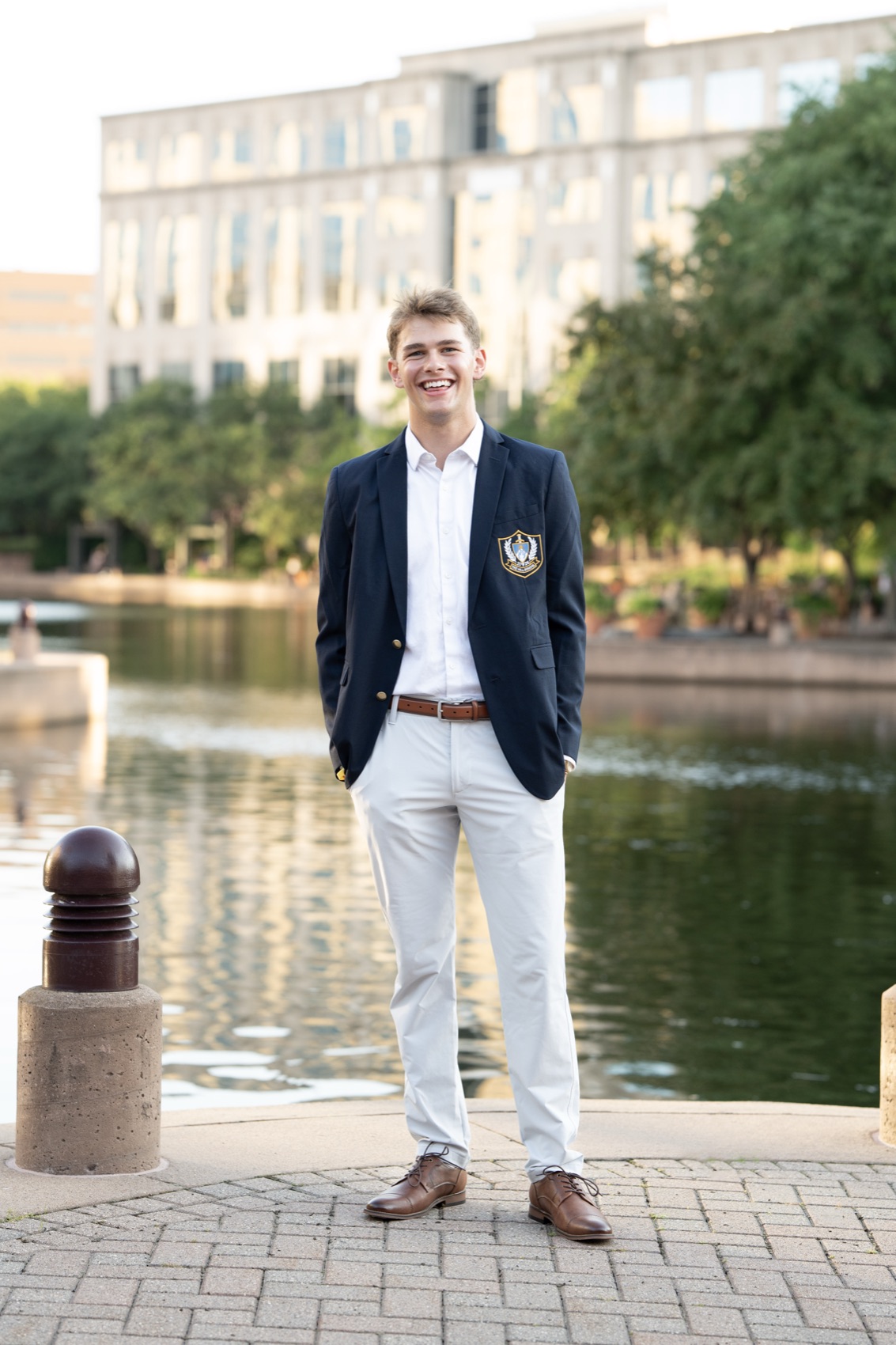 Polished full-length senior portrait in a navy blazer by the water